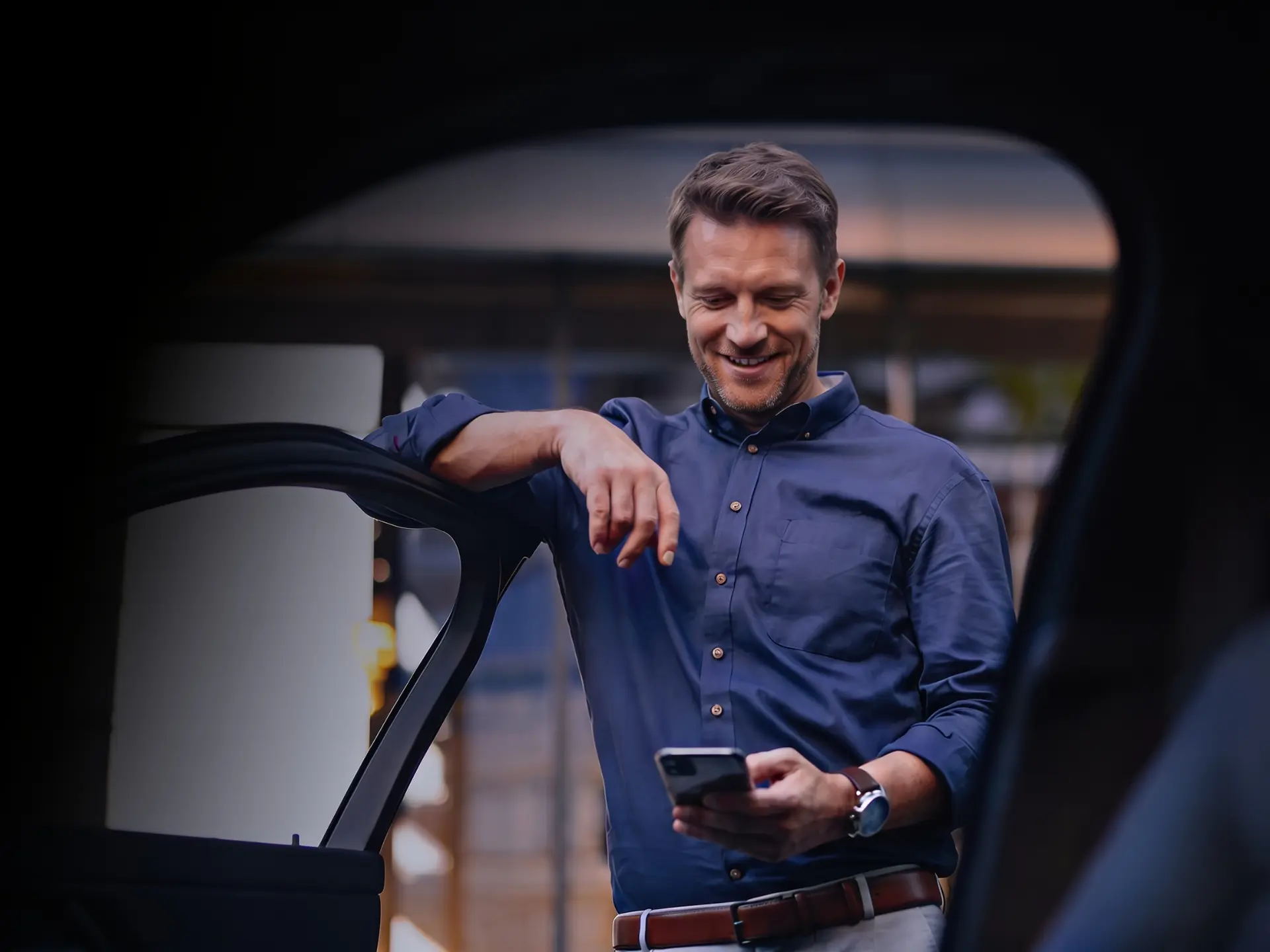 Man checking an approved MTX transfer on his phone next to a car